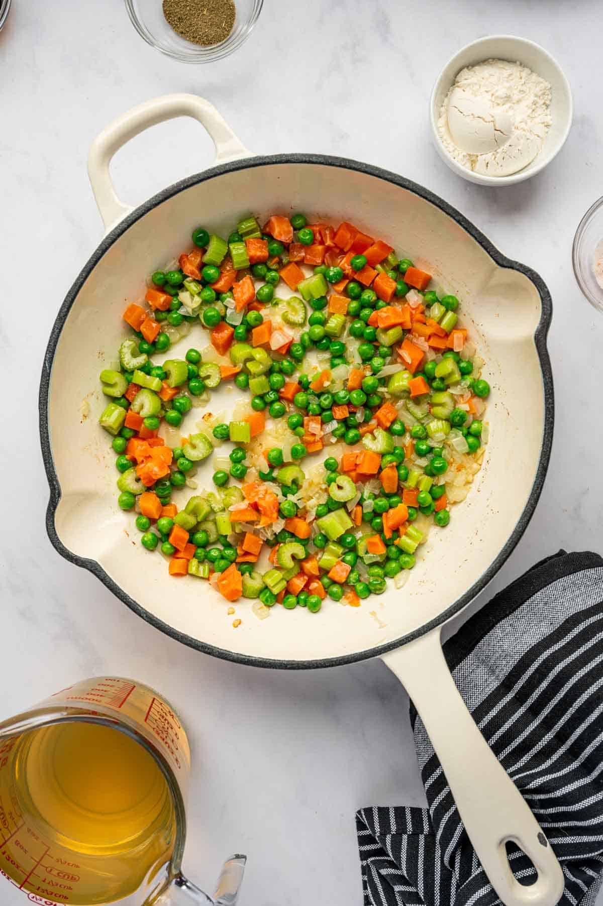 In a skillet veggies being added and sautéed.