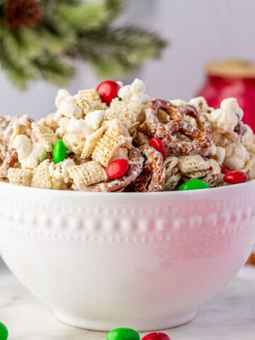 Festive bowl of Christmas Crunch mix surrounded by ornaments and candy canes — ideal for holiday parties and gift ideas.