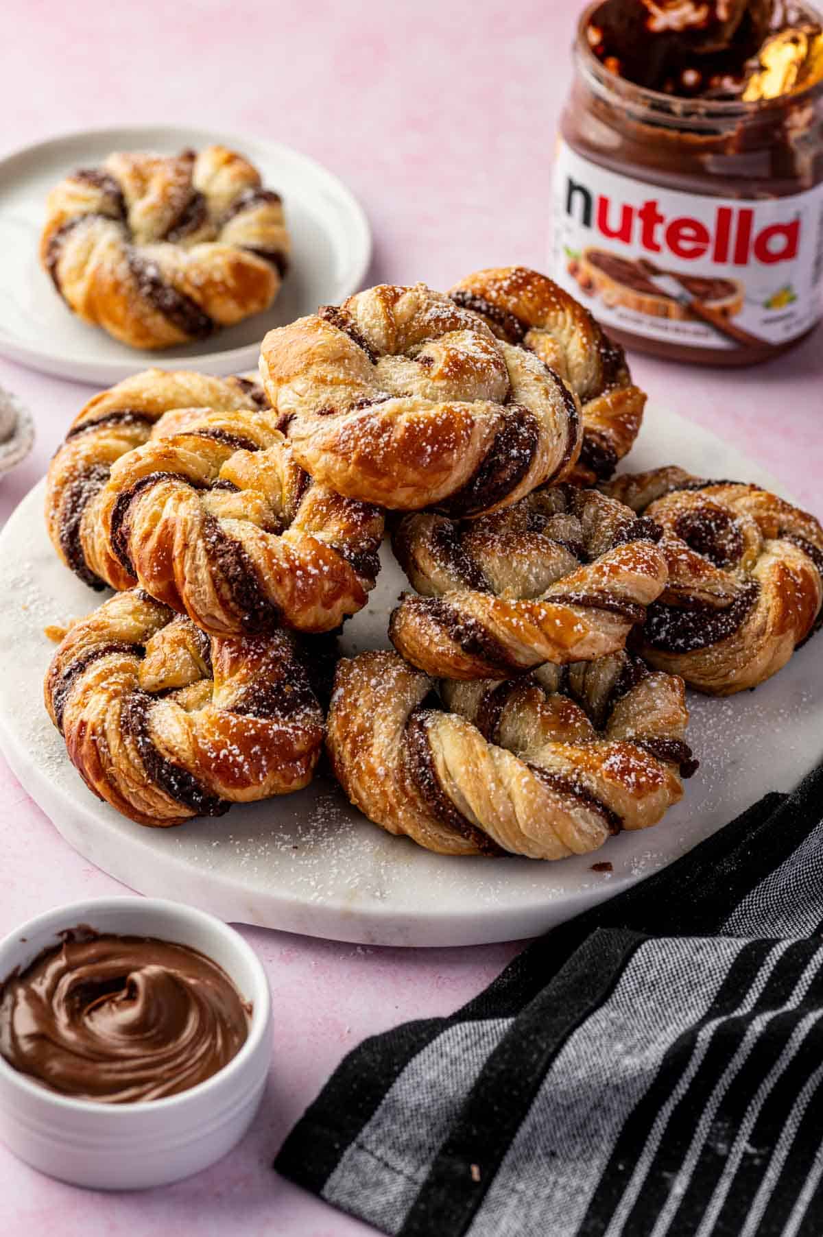 Freshly baked Nutella pastries pleced in a white marble plate with visible flaky texture.