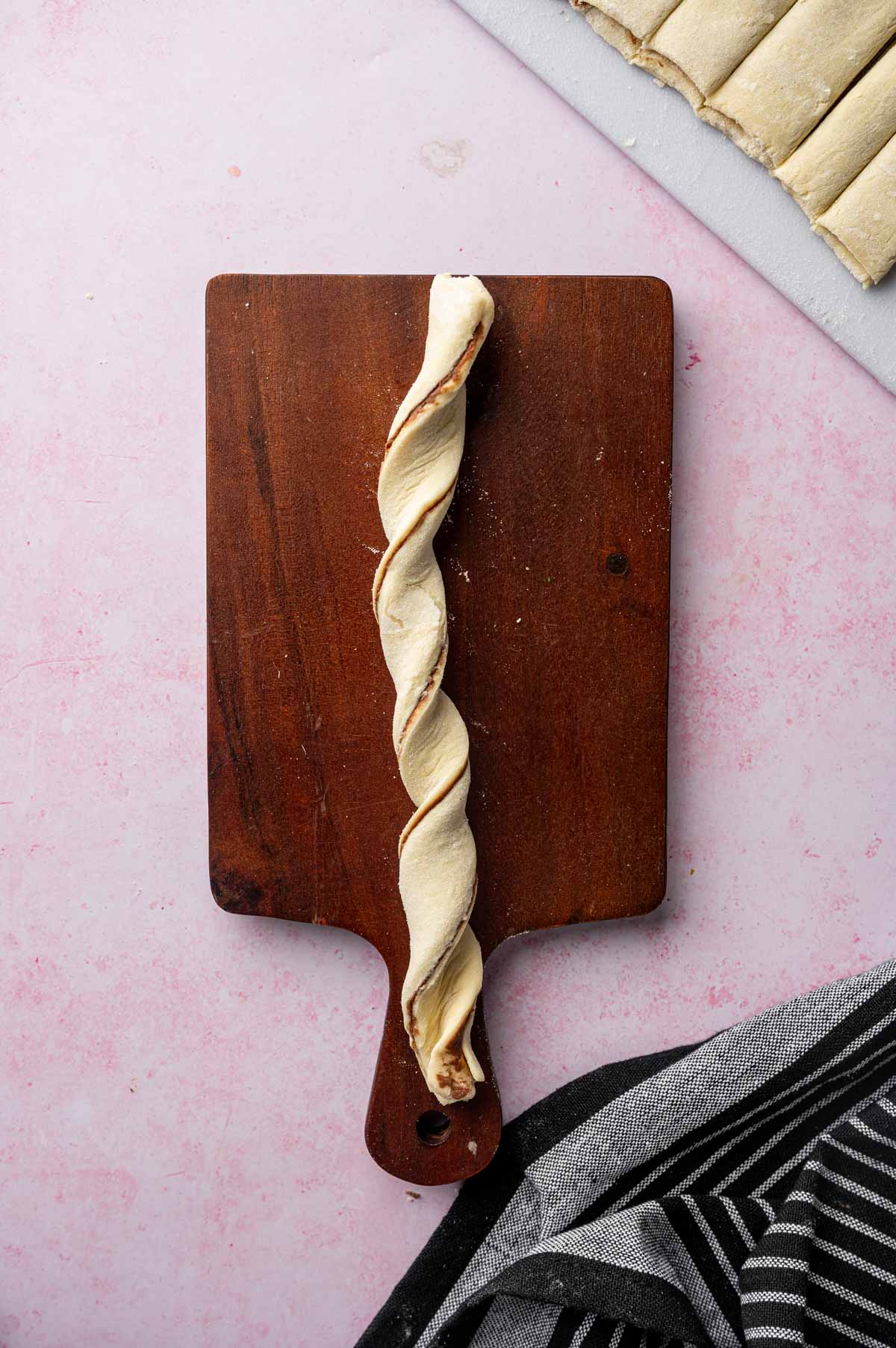 Hands twisting puff pastry strips to form Nutella puff pastry braids.