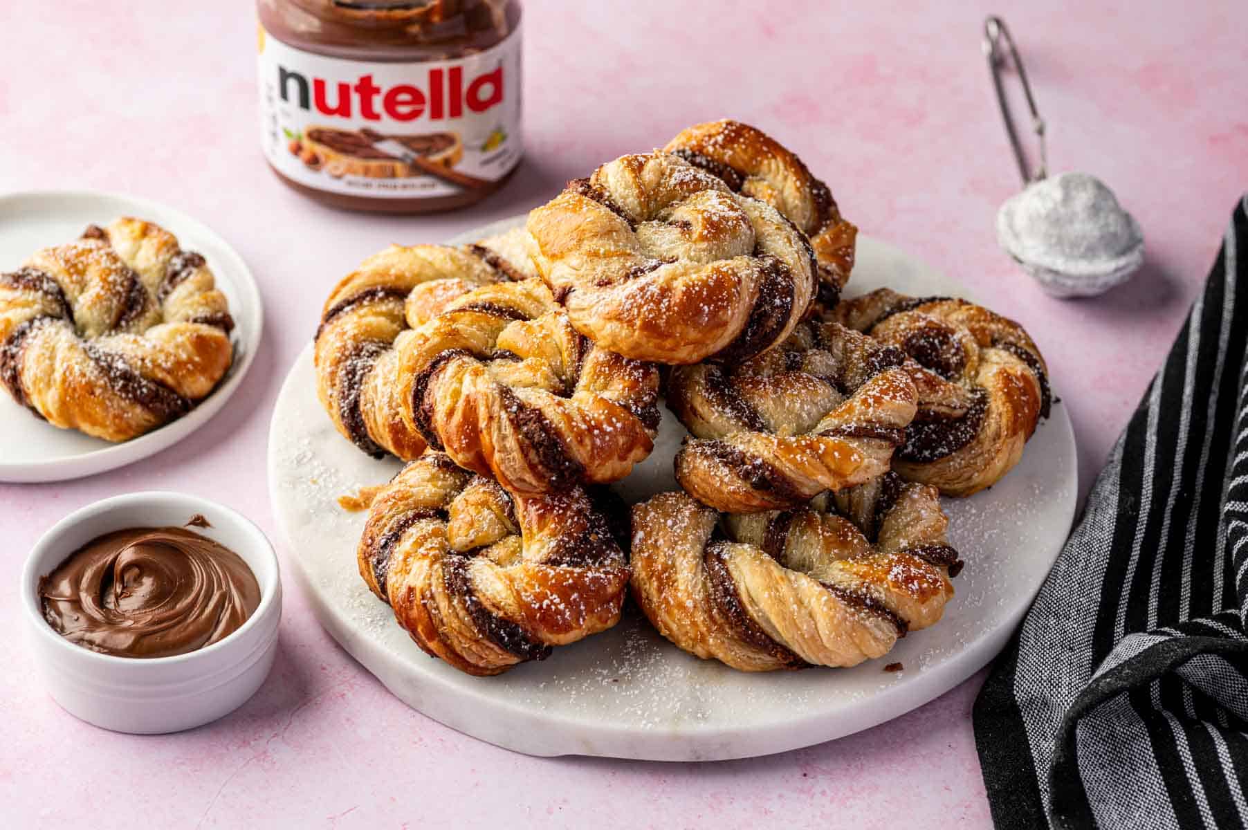 Golden, flaky air fryer Nutella puff pastry pieces arranged on a marble tray.