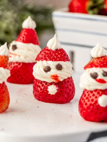 Close-up of Strawberry Santas made with fresh strawberries, cream cheese frosting, and mini chocolate chip eyes — cute and festive Christmas dessert.