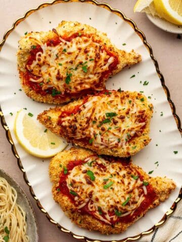 Plated air fryer chicken parmesan in a white oval plate with gold rim.