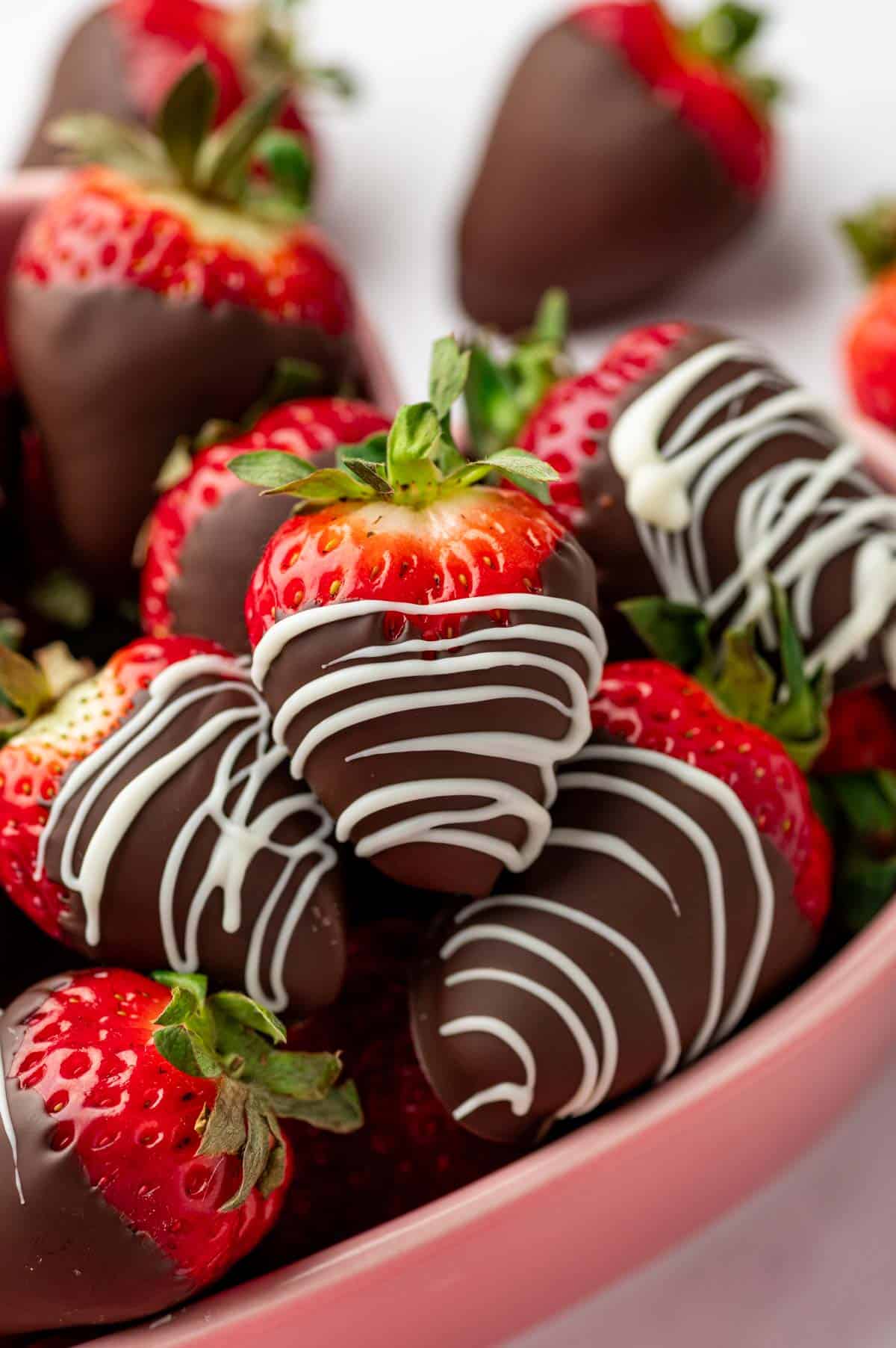 Chocolate covered strawberries placed in a pink heart bowl.