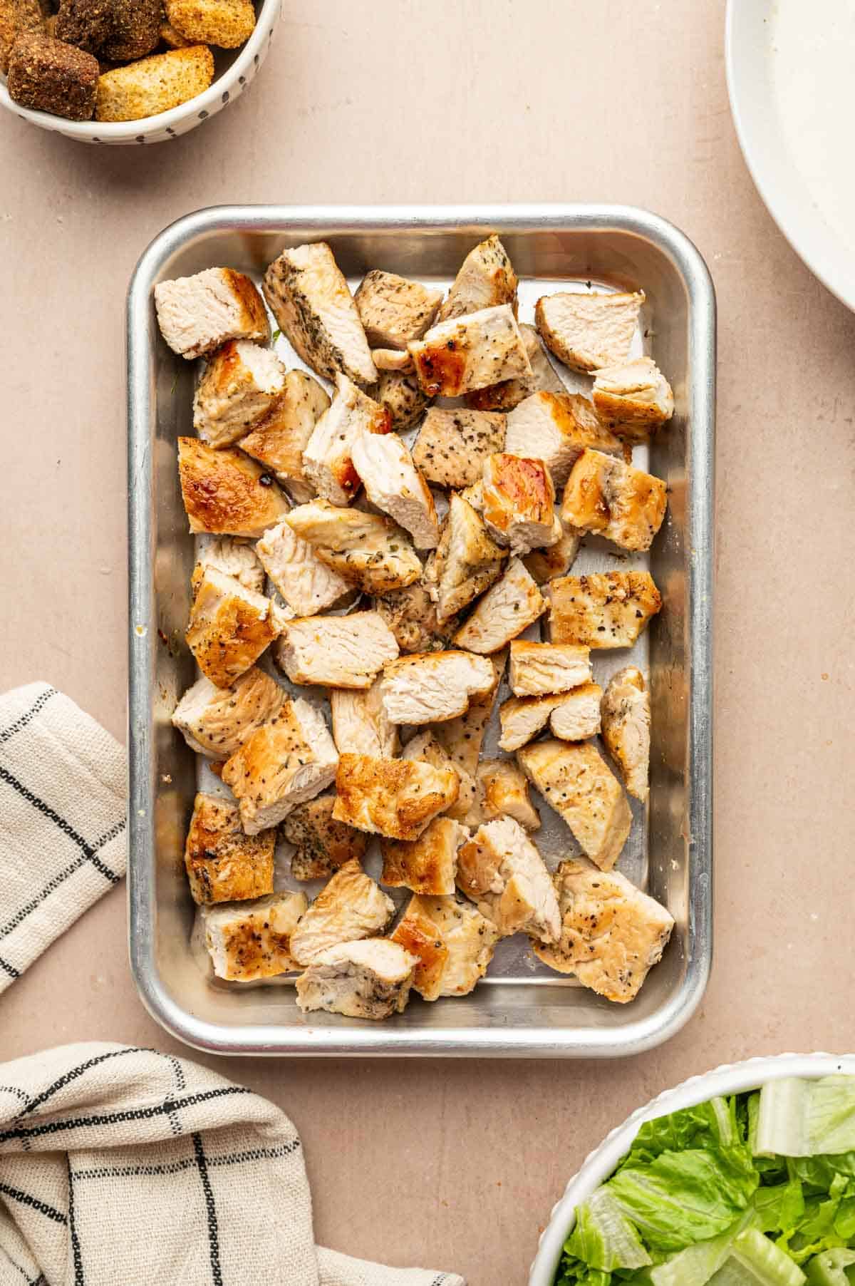 Cooked chicken breasts being chopped into bite size pieces for making salad.