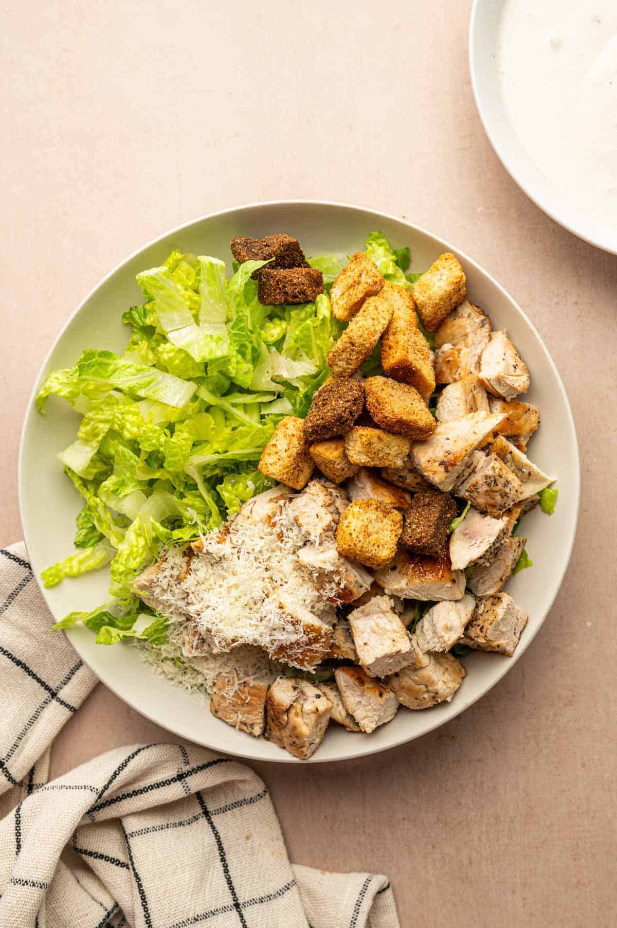 Tossing romaine with chicken pieces, parmesan cheese