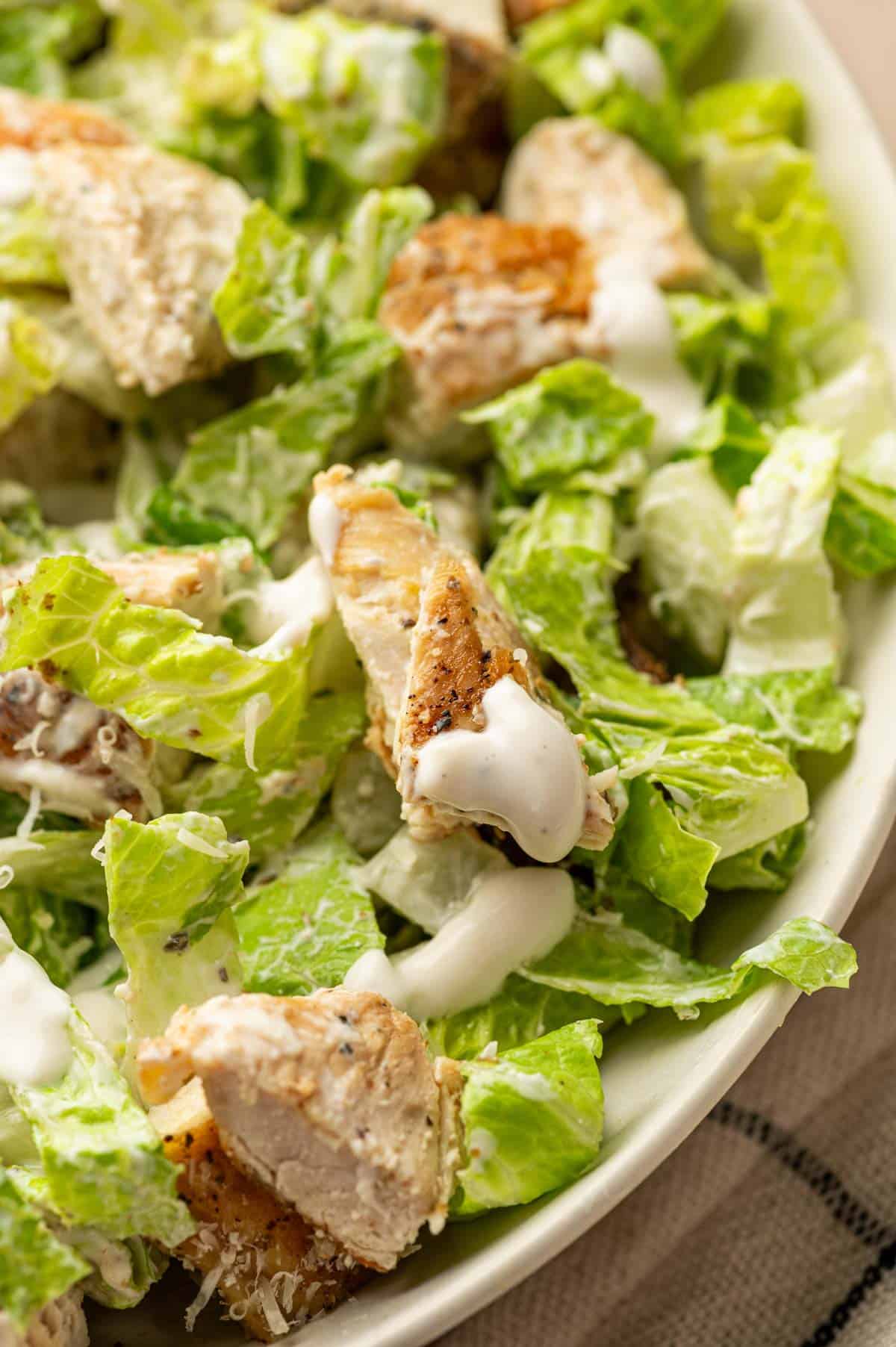 Pouring creamy Greek yogurt Caesar dressing into the salad