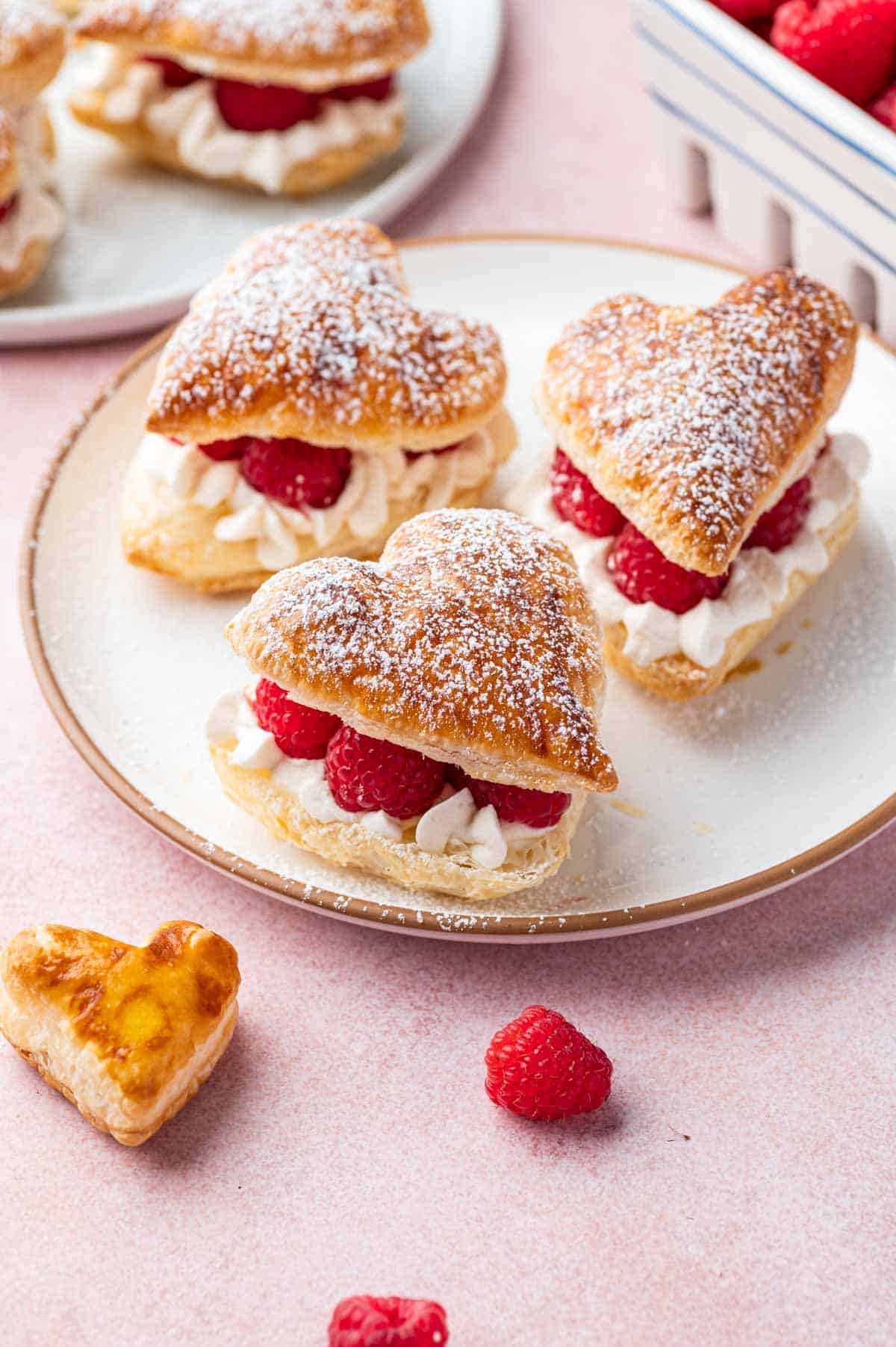 Side angle shot of puff pastry hearts with powdered sugar and drizzle