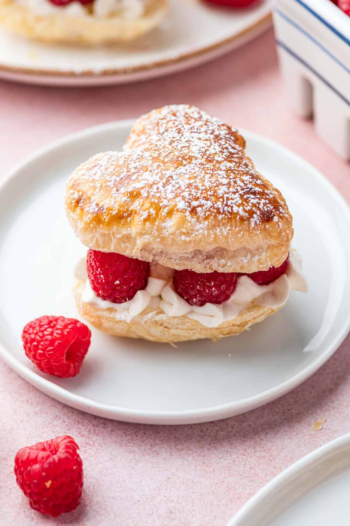 Golden puff pastry hearts on a white plate.
