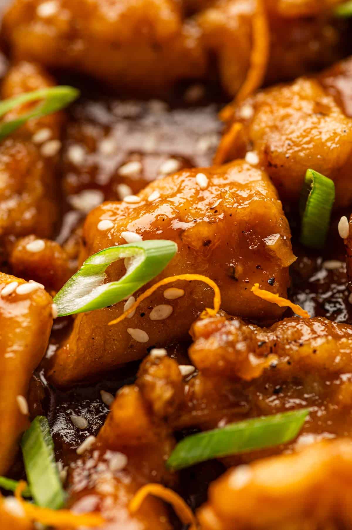 close up shot of Sticky orange chicken sauce coating crispy chicken pieces