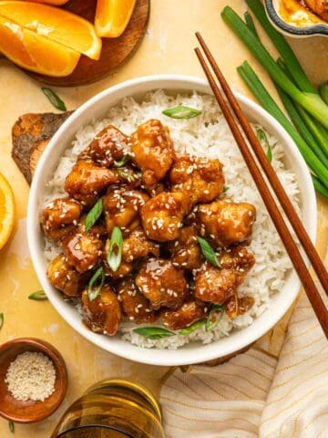 Air fryer orange chicken and rice served in a bowl with sesame seeds and green onions