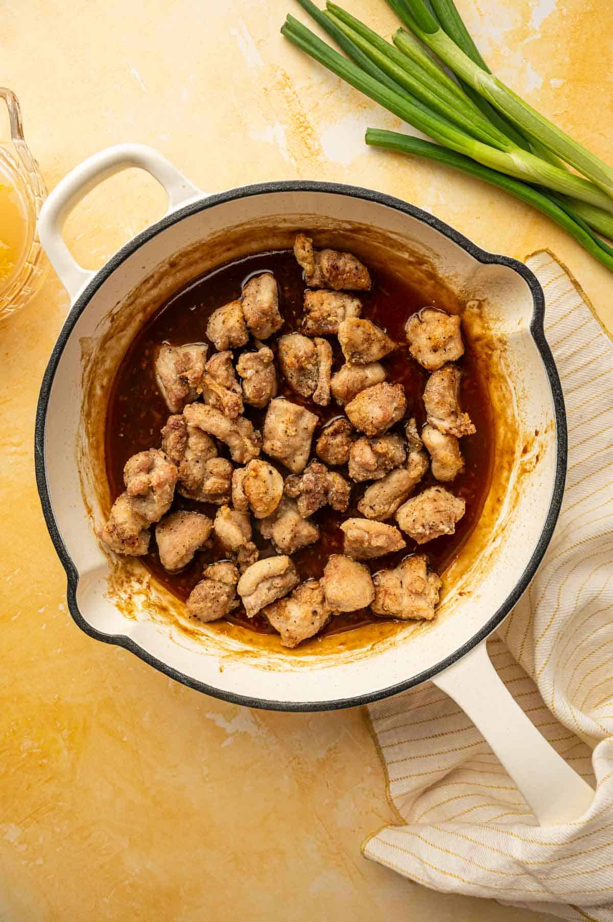 crispy chicken added to the orange sauce in the skillet.