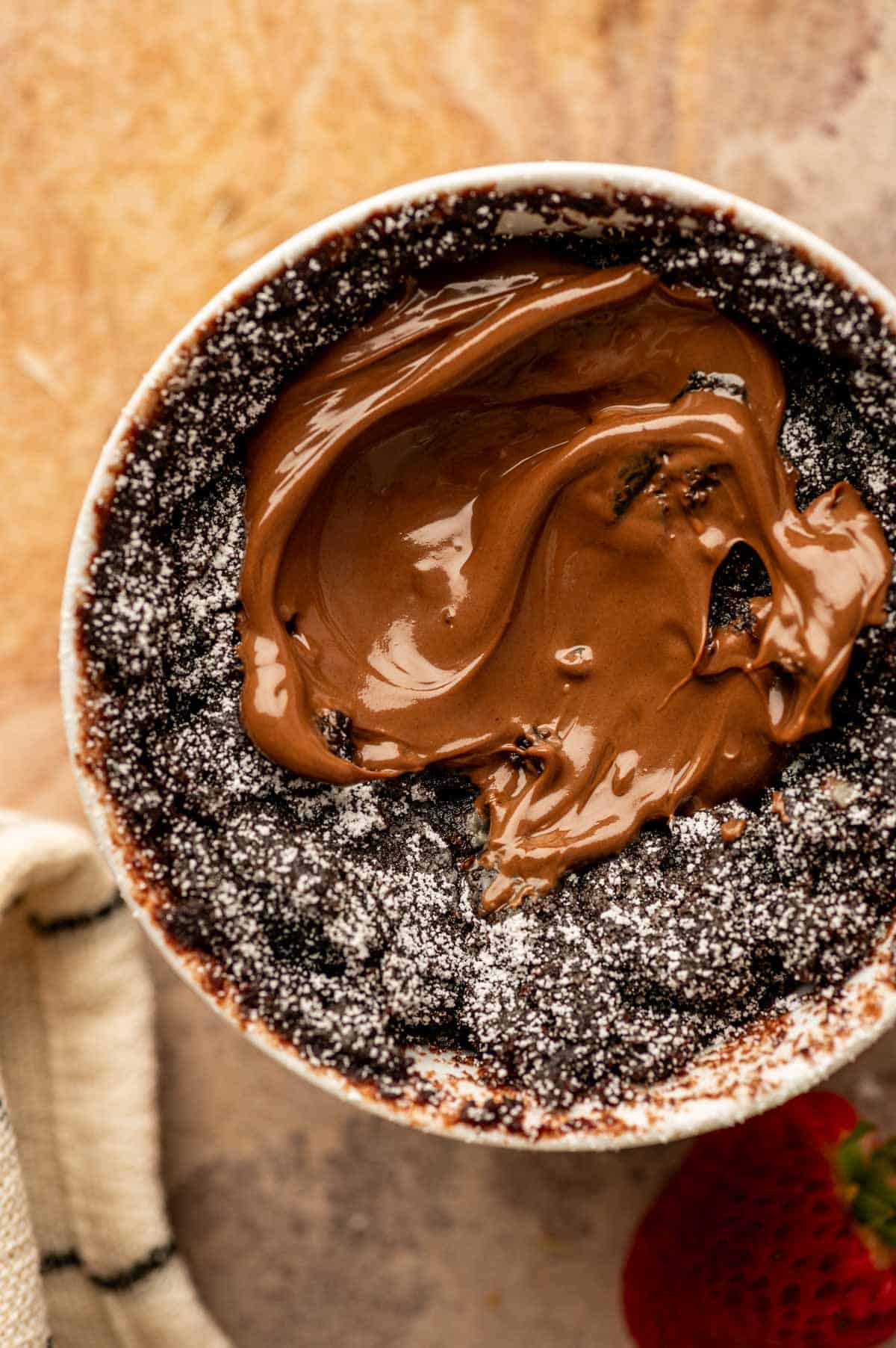 Microwave Nutella mug cake just cooked, set on top with soft center and topped with nutella