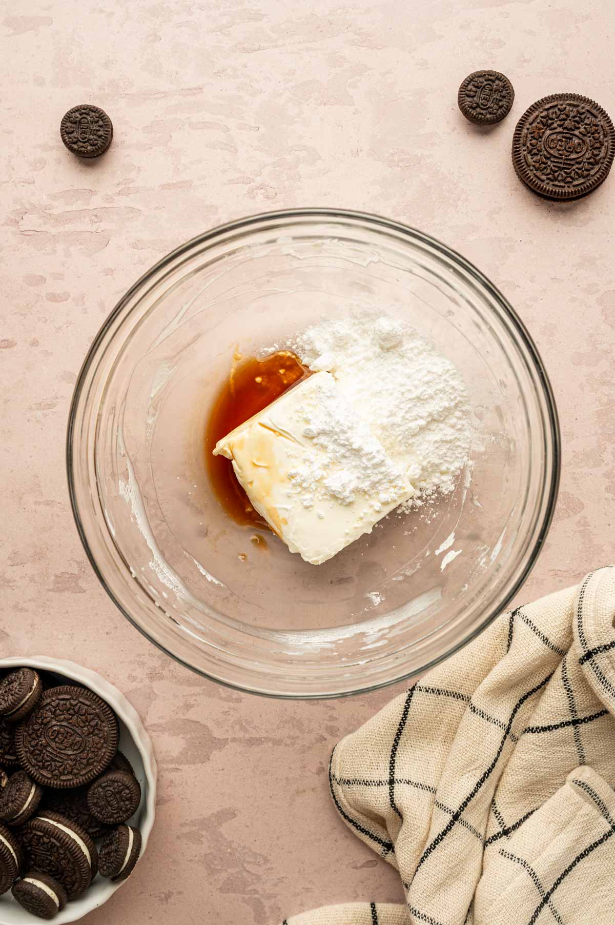 Cream cheese, sugar and vanilla being added to a glass bowl.