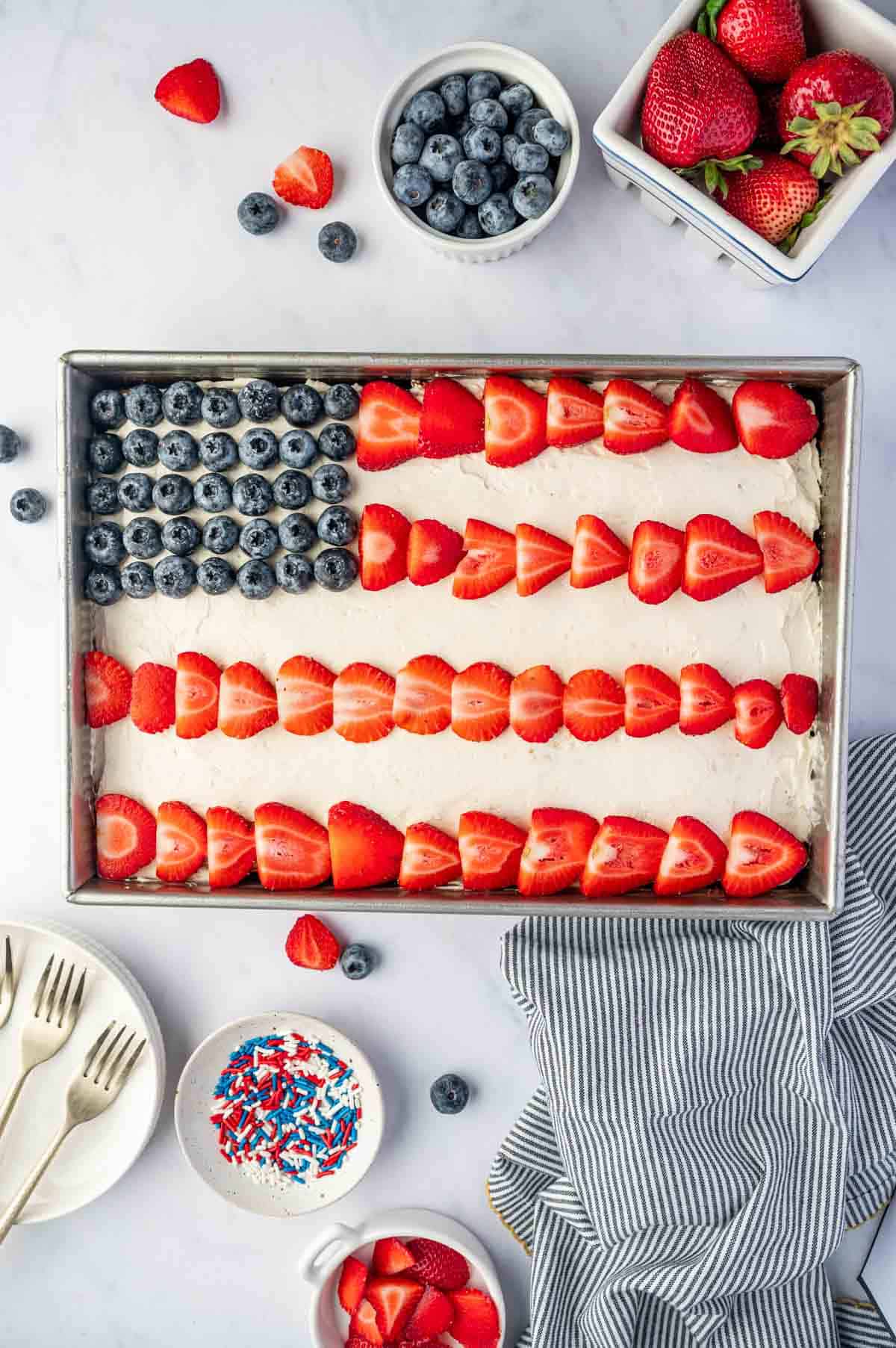 Overhead shot of 4th of July flag cake with blueberries and rows of strawberries on vanilla buttercream