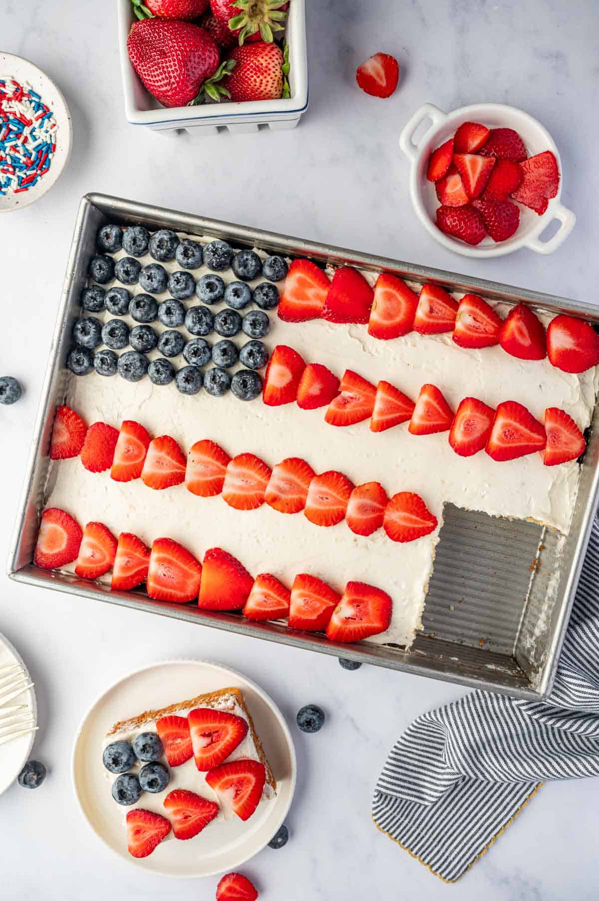 Rectangular flag cake on a serving tray with fruit flag decoration for summer parties, a slice is taken