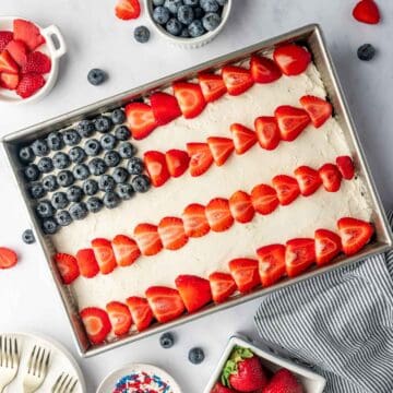 Patriotic flag cake recipe decorated with fresh strawberries and blueberries on top of the cake