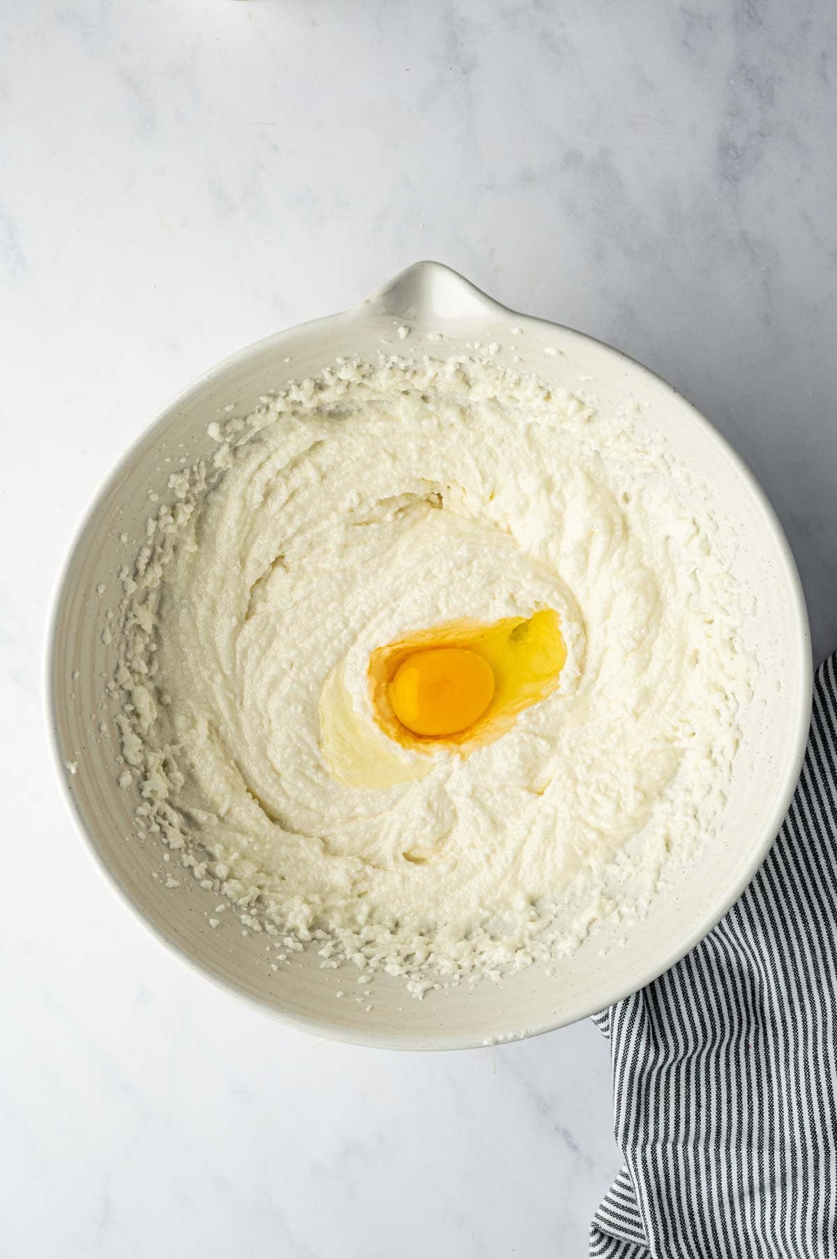 Adding egg to the cake batter mixture.