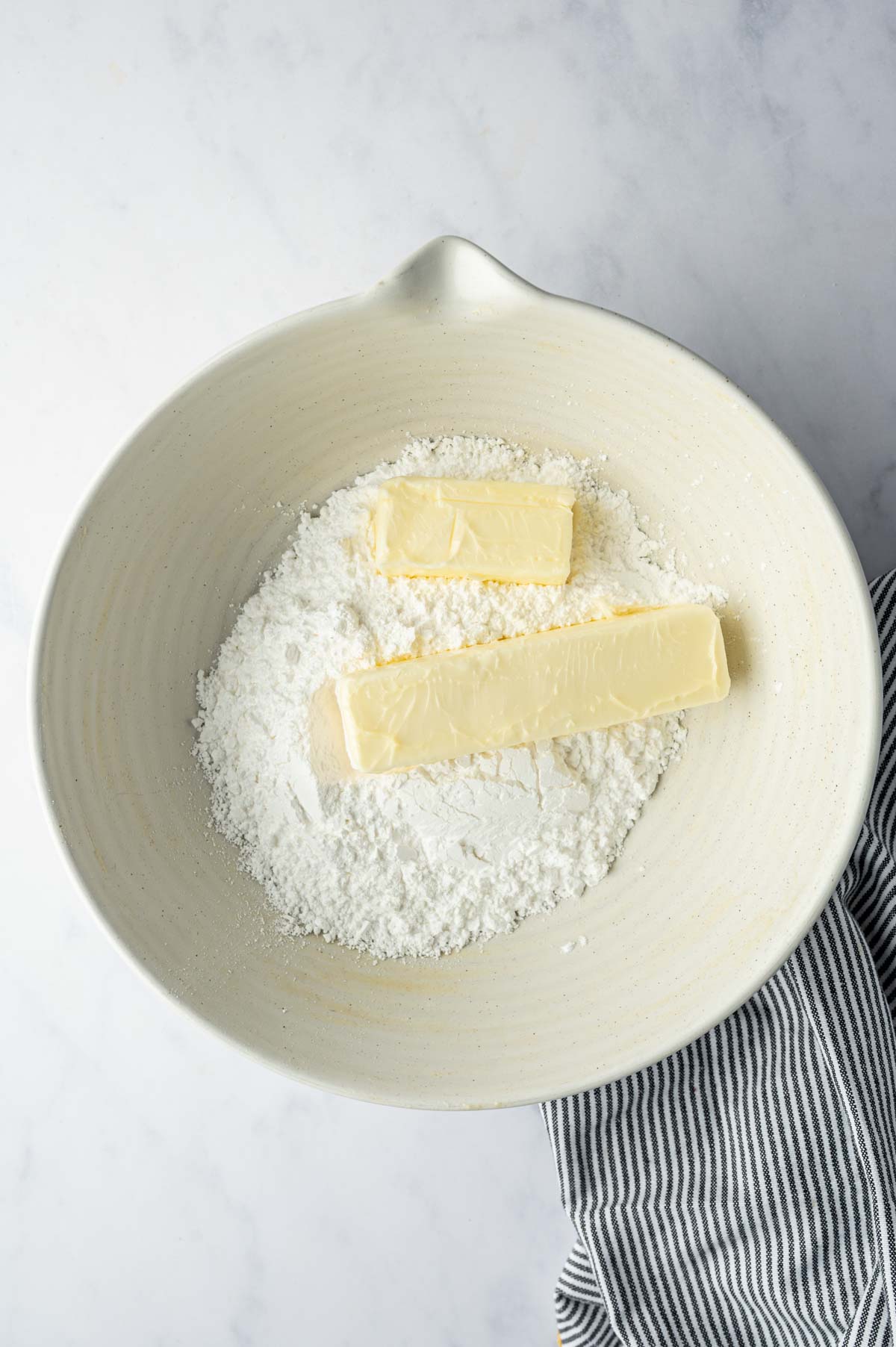 In a bowl confectioners sugar and butter is ready for making vanilla buttercream