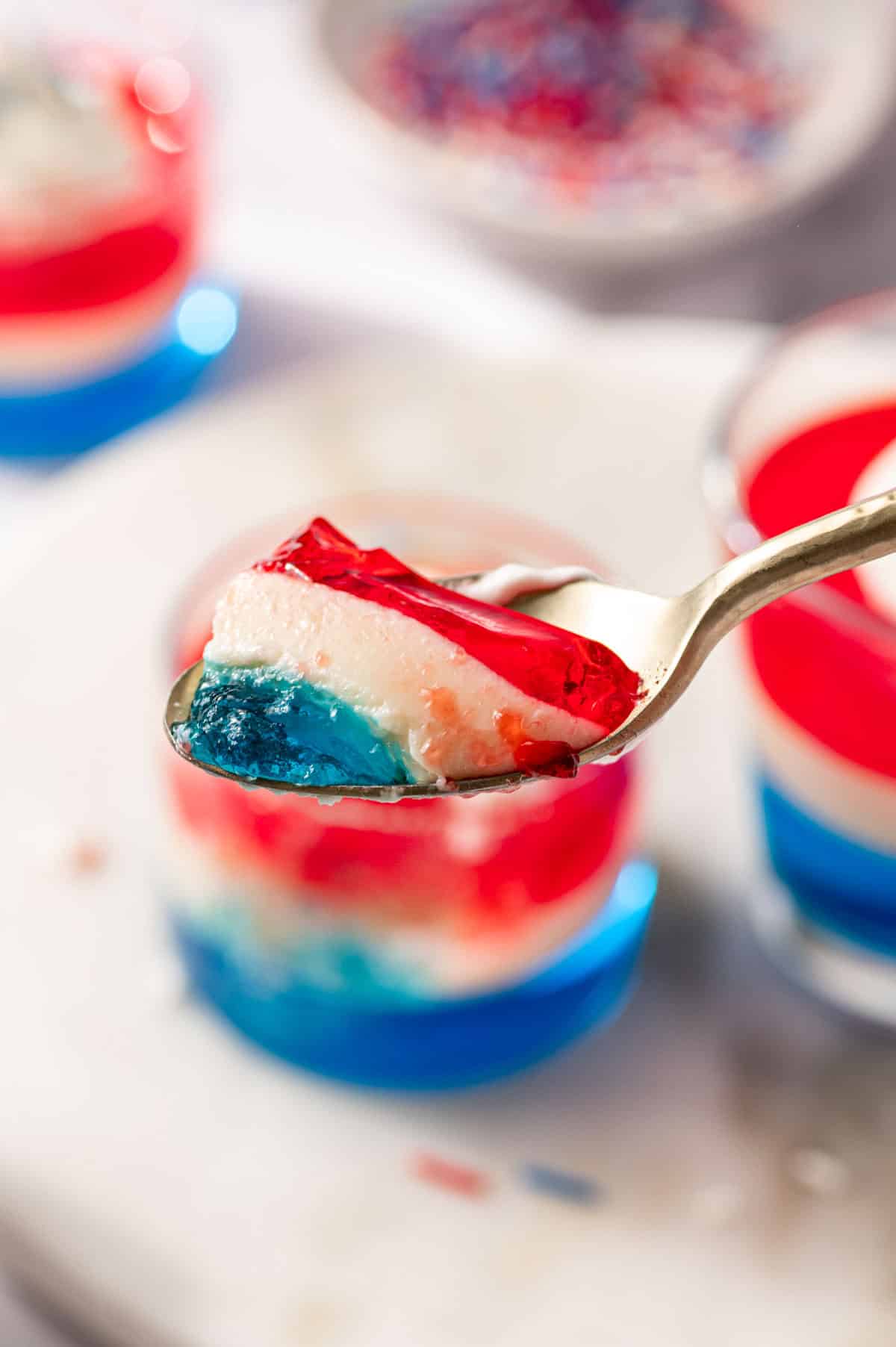 Spoonful of red, white and blue jello taking a bite.