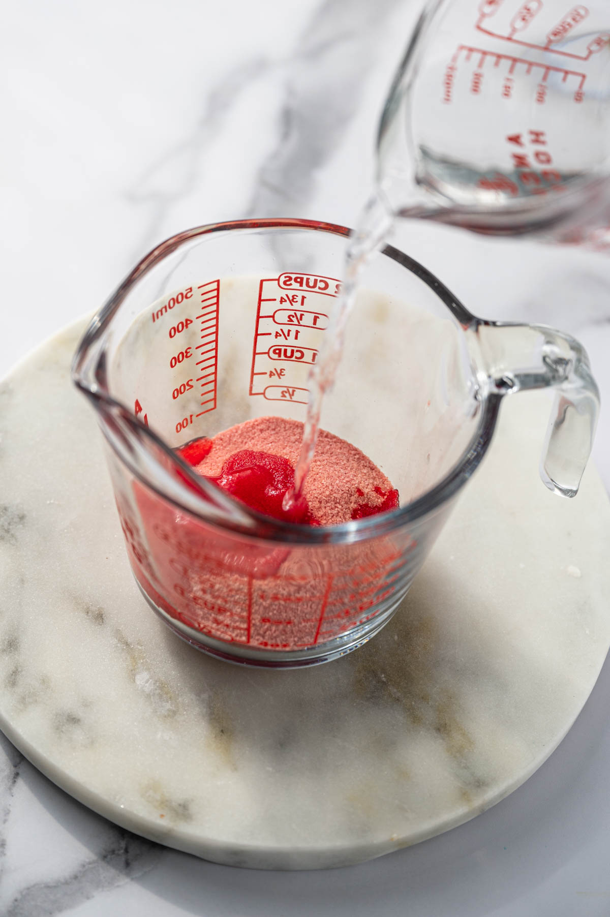 Strawberry jello being prepared in a glass bowl