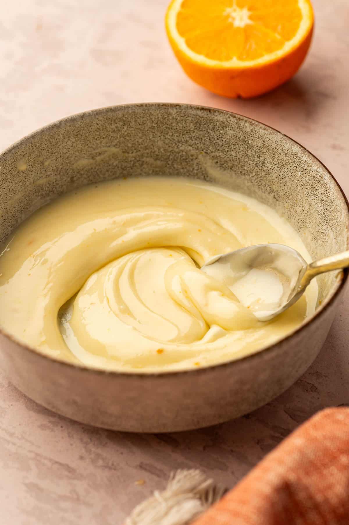 Orange icing being mixed in a bowl.