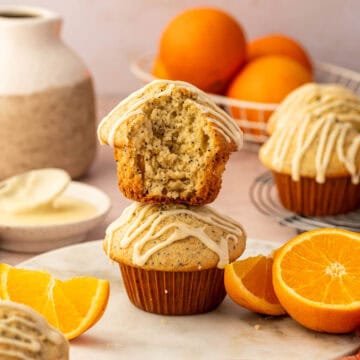 Close-up shot of orange poppy seed muffin topped with fresh orange glaze stacked one above the other.