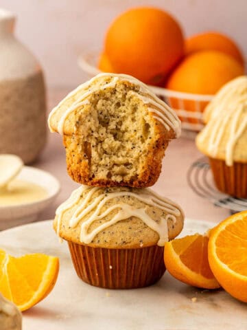 Close-up shot of orange poppy seed muffin topped with fresh orange glaze stacked one above the other.