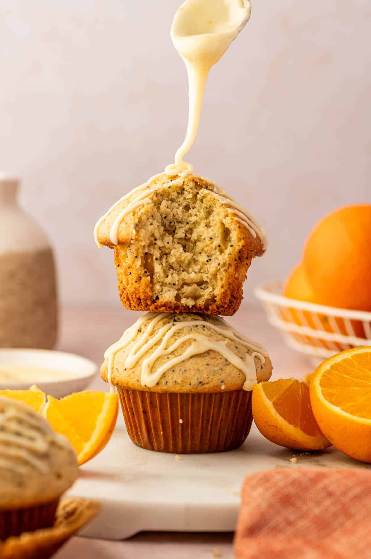 Bakery-style orange poppy seed muffins with orange zest and poppy seeds with orange icing drizzle on top.