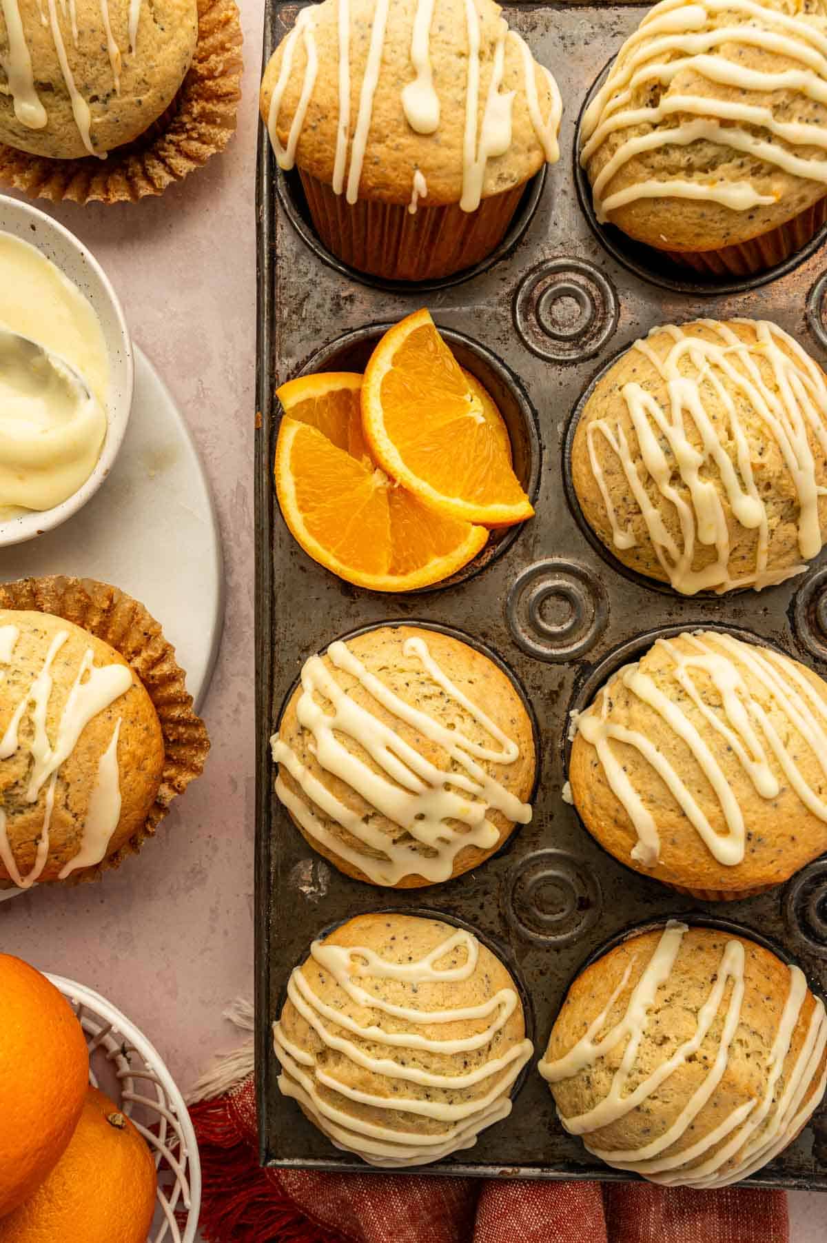 Freshly baked orange poppy seed muffins in a muffin pan after icing