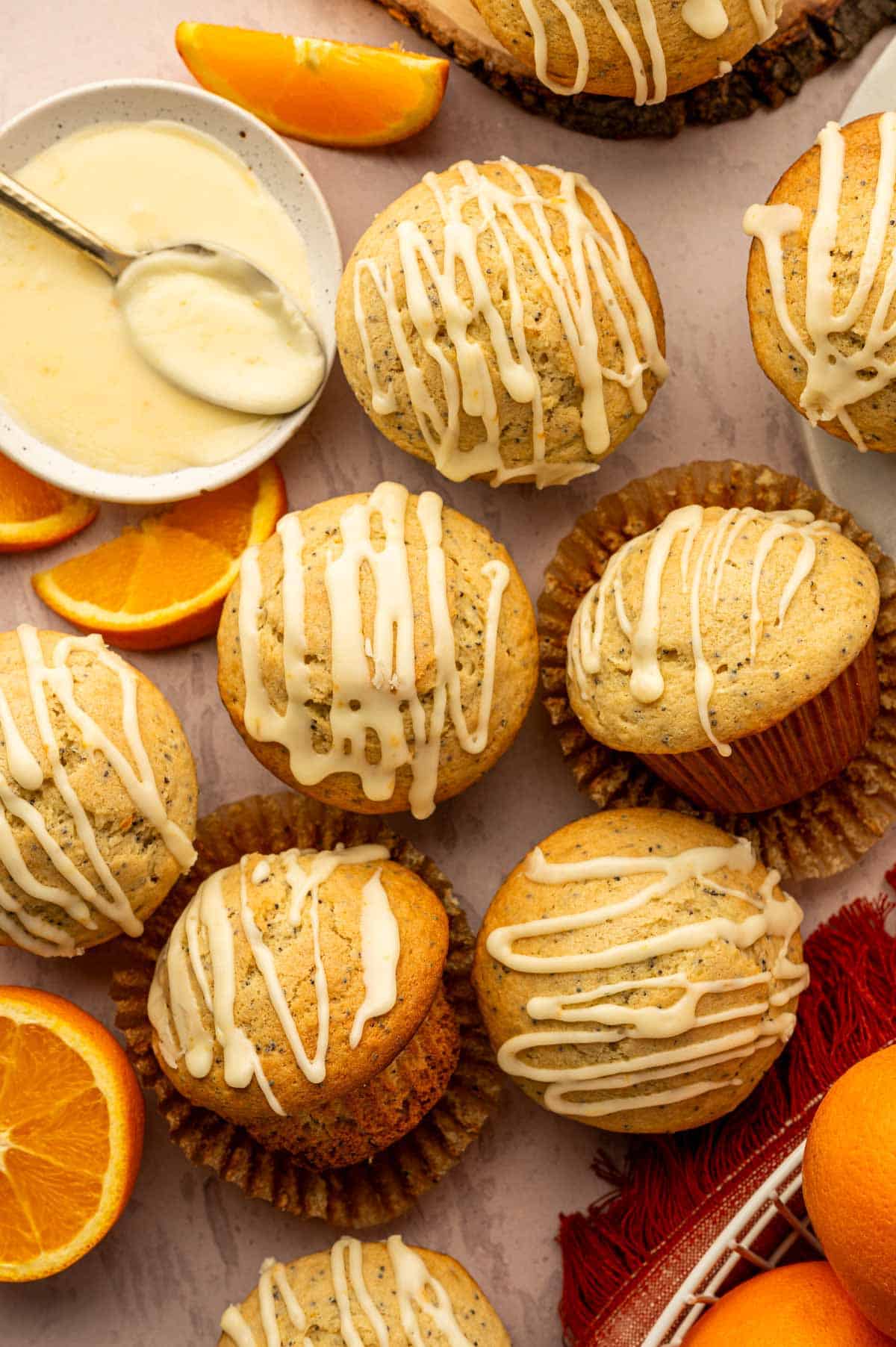 Top-down view of orange poppy seed muffins with glossy orange glaze on the side.