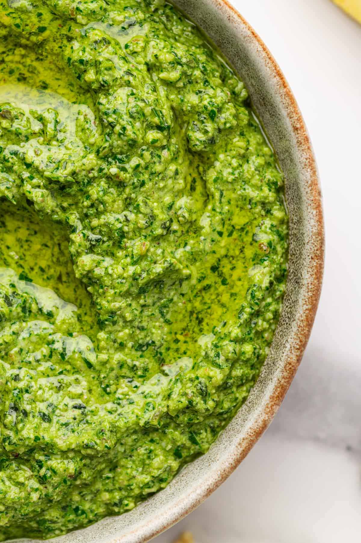close up shot of basil pesto in a grey off white bowl
