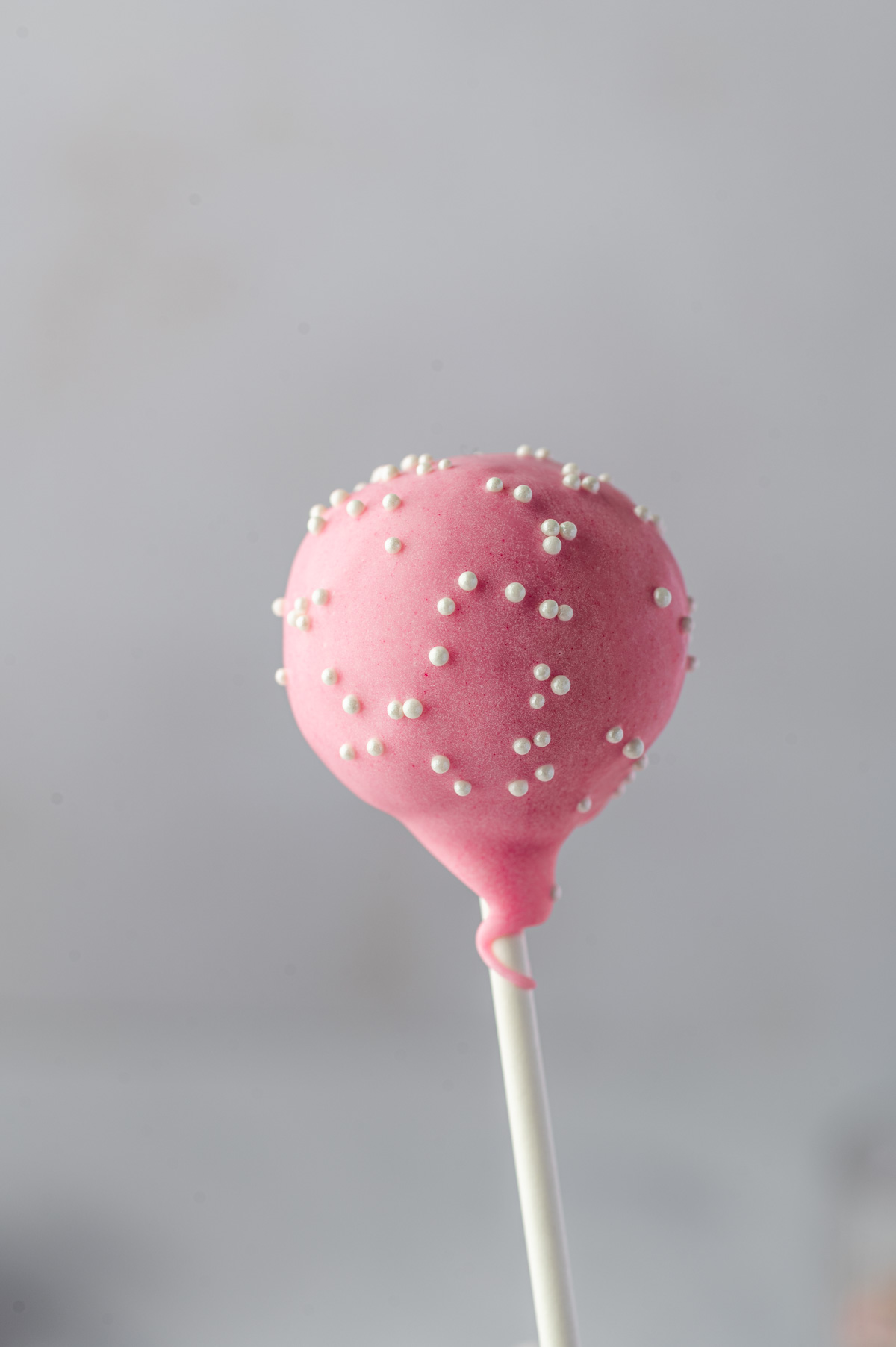 Close-up of a pink birthday cake pop covered in white sprinkles