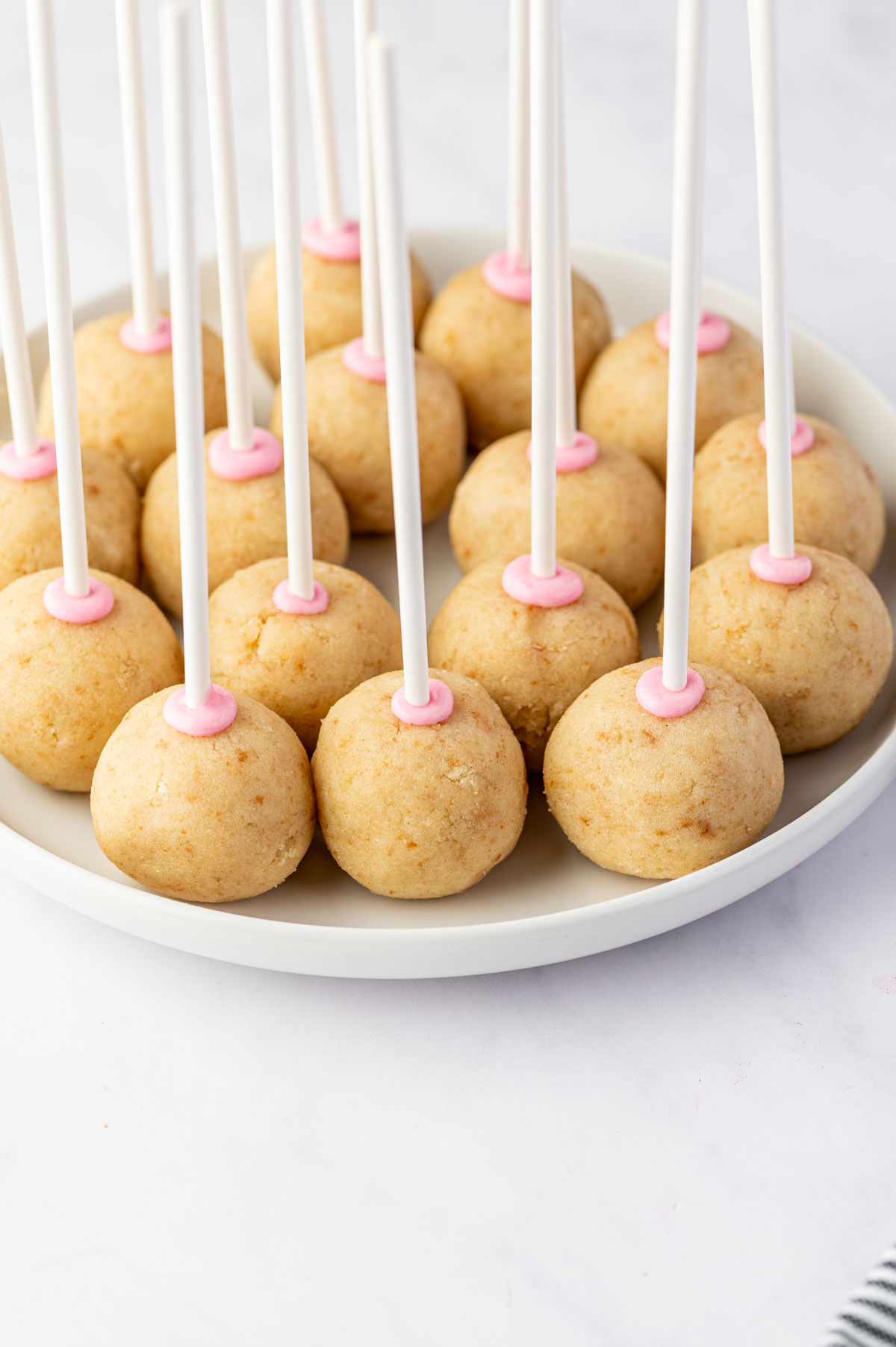 Inserting cake pop sticks into chilled birthday cake balls