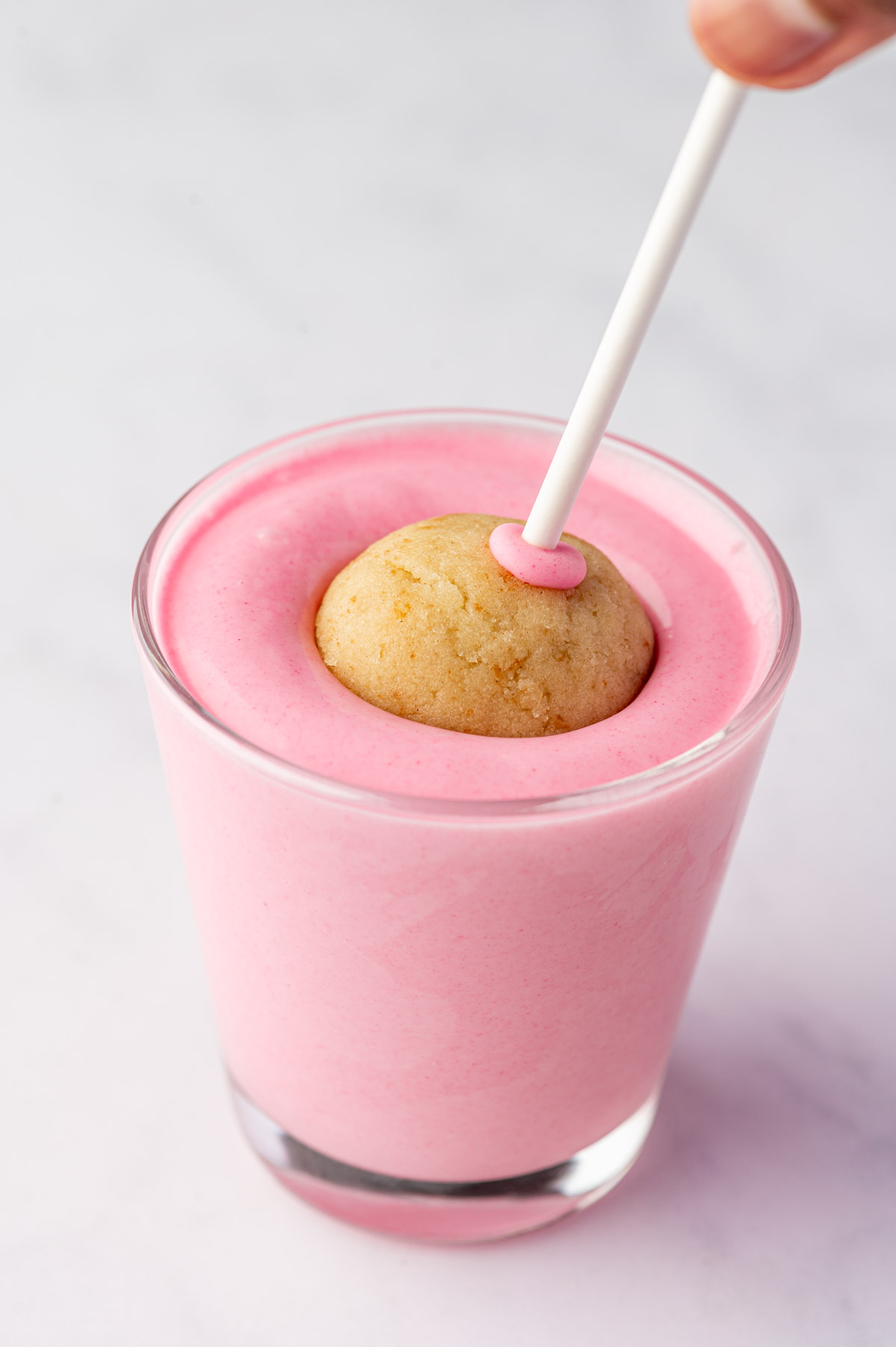 Dipping birthday cake pops into melted pink candy coating