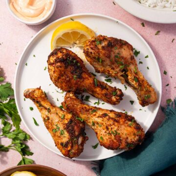 Crispy air fryer chicken drumsticks served on a platter with fresh parsley garnish.