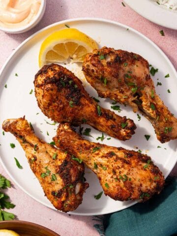 Crispy air fryer chicken drumsticks served on a platter with fresh parsley garnish.
