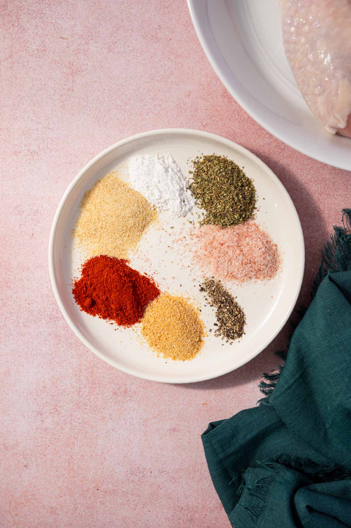Seasonings added to a white plate for making air fryer chicken