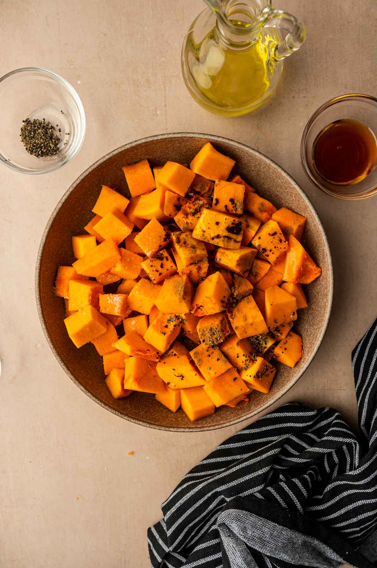 Cubed butternut squash tossed with maple syrup, cinnamon, and seasonings before air frying.