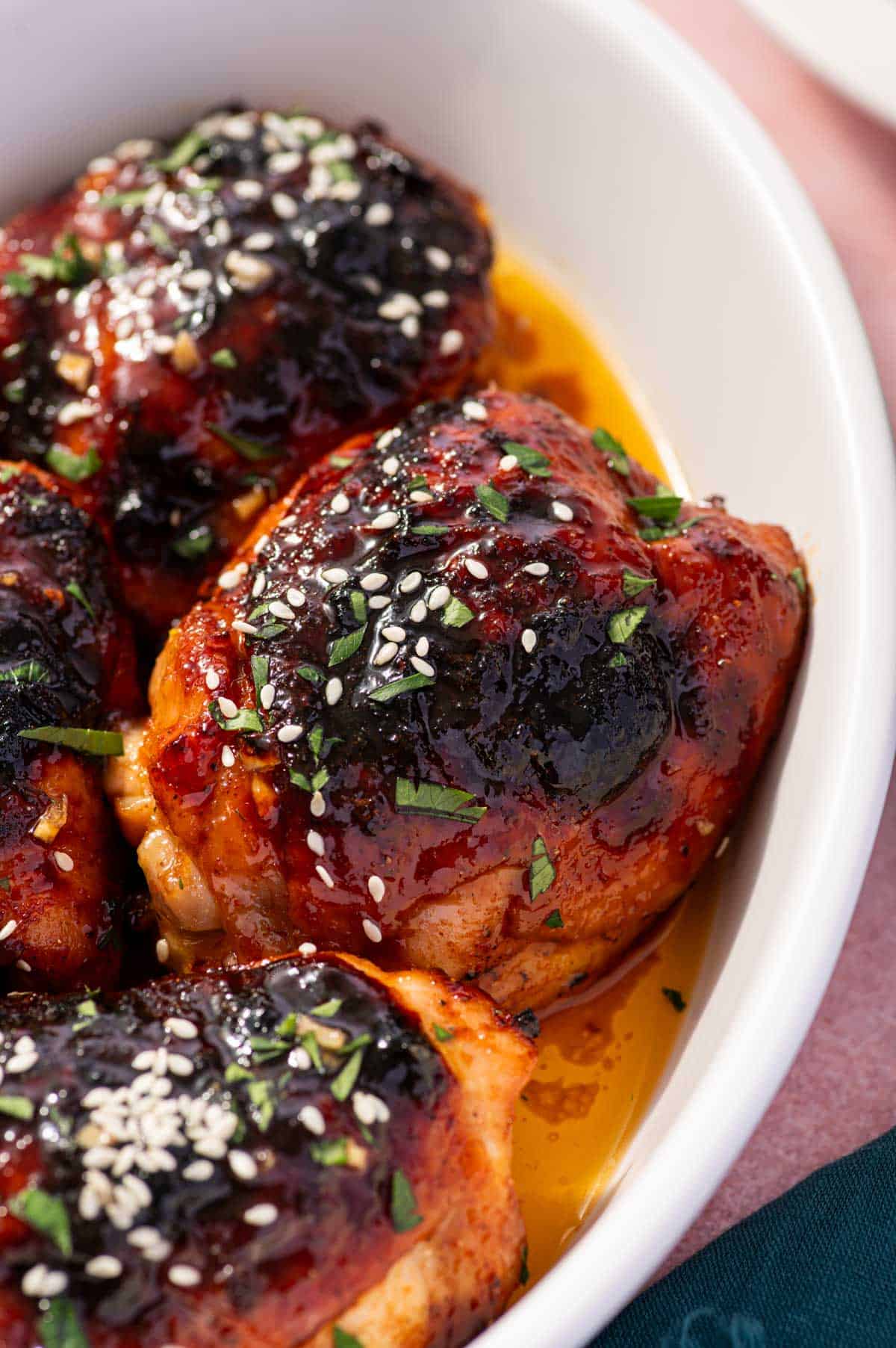 Close-up of caramelized honey garlic chicken thighs, garnished with sesame seeds.