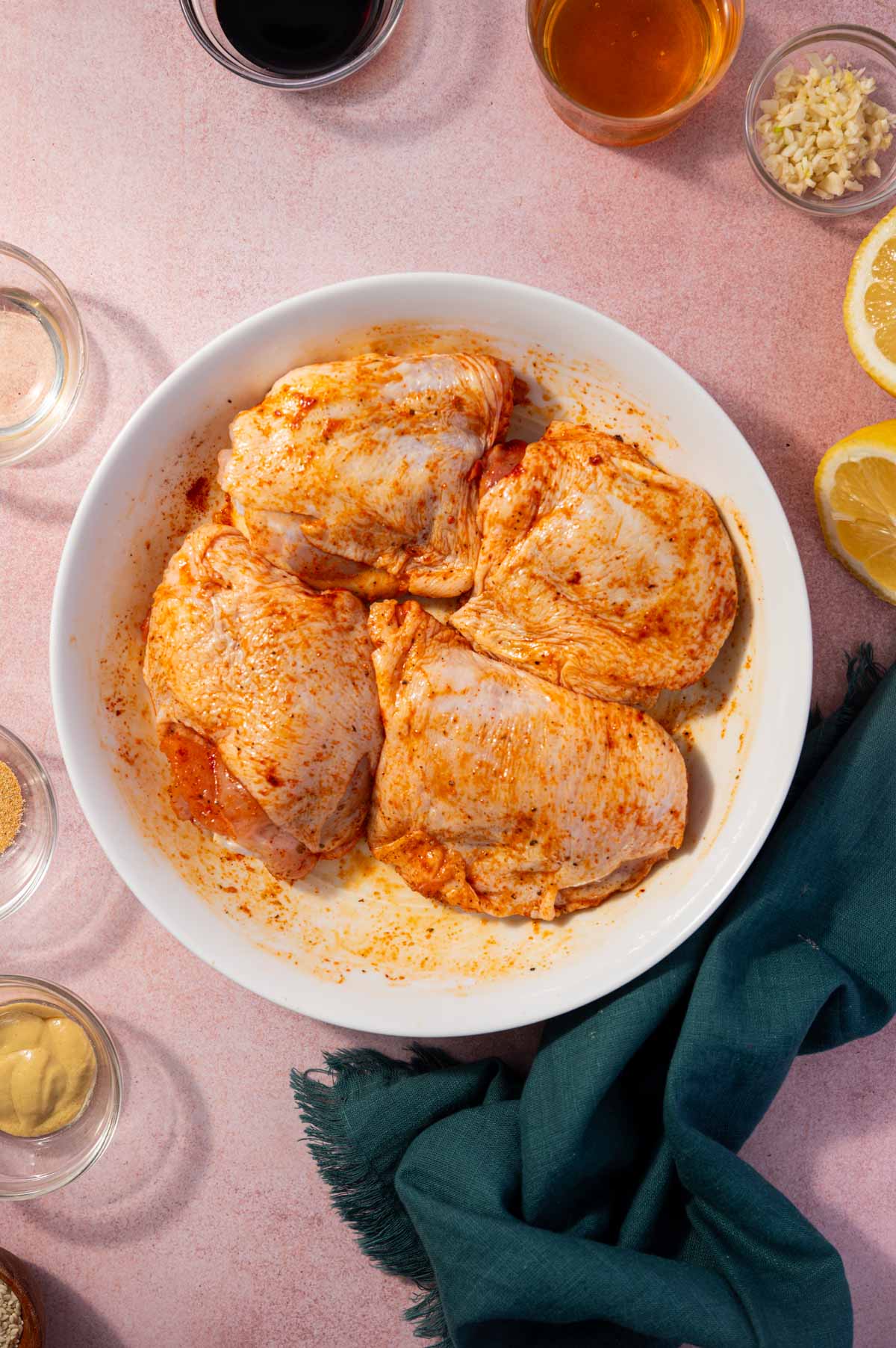 Seasoning chicken thighs before baking.