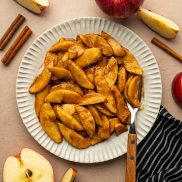 Beautifully caramelized air fryer apple slices placed in a plate with a fork.