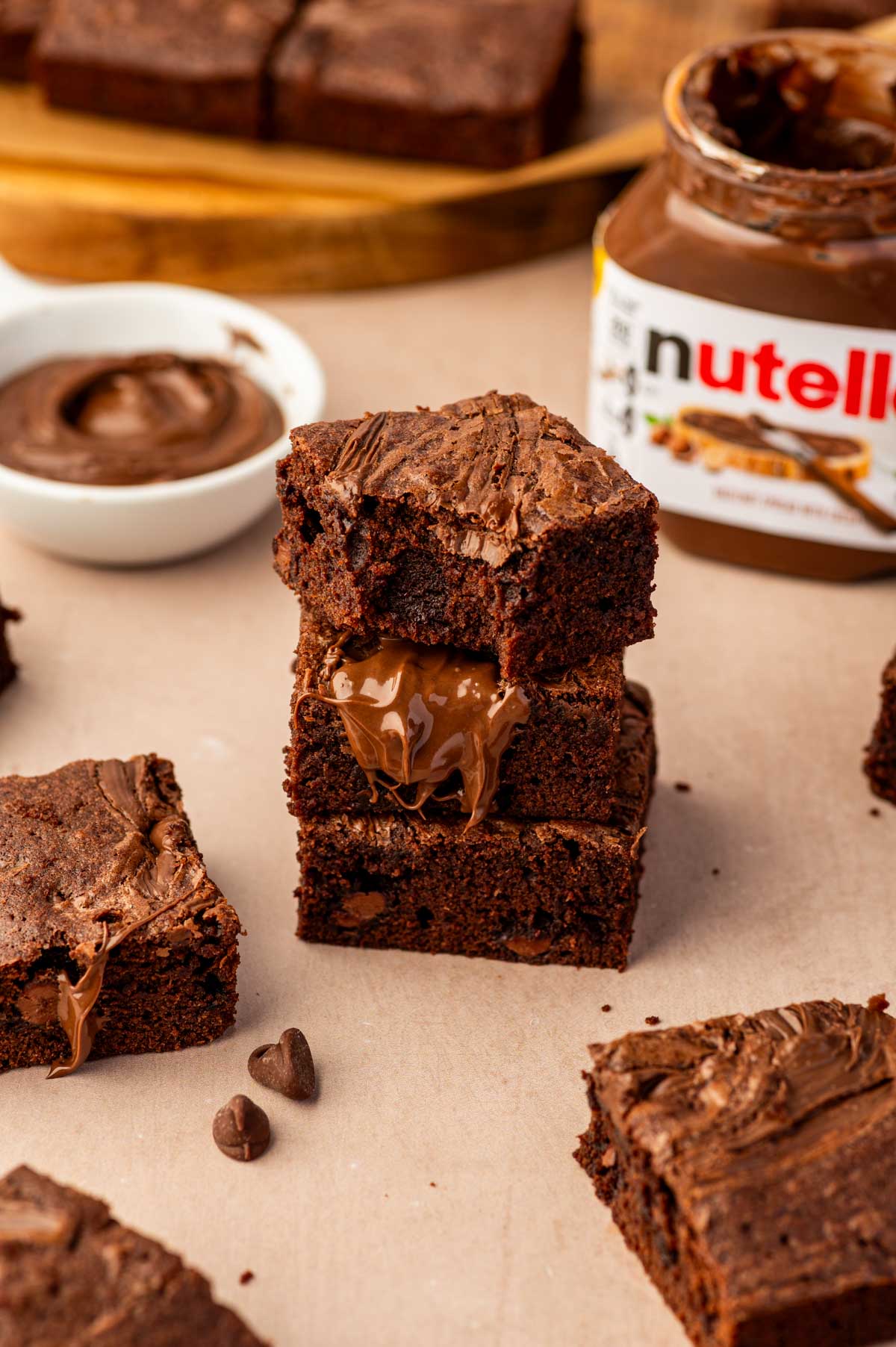 Stack of fudgy Nutella brownies on a serving plate with nutella drizzle oozing out.