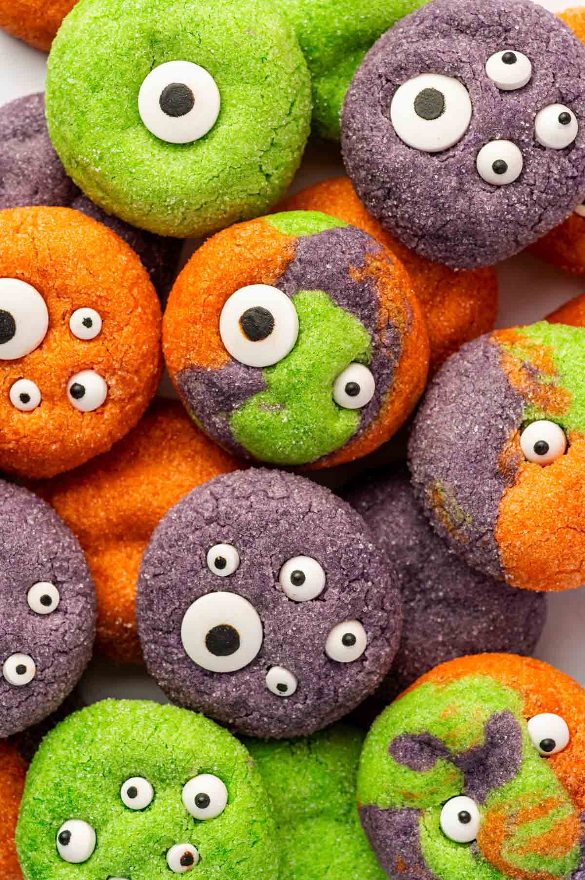 Halloween Monster Eye Cookies in purple, orange, and green decorated with candy eyeballs