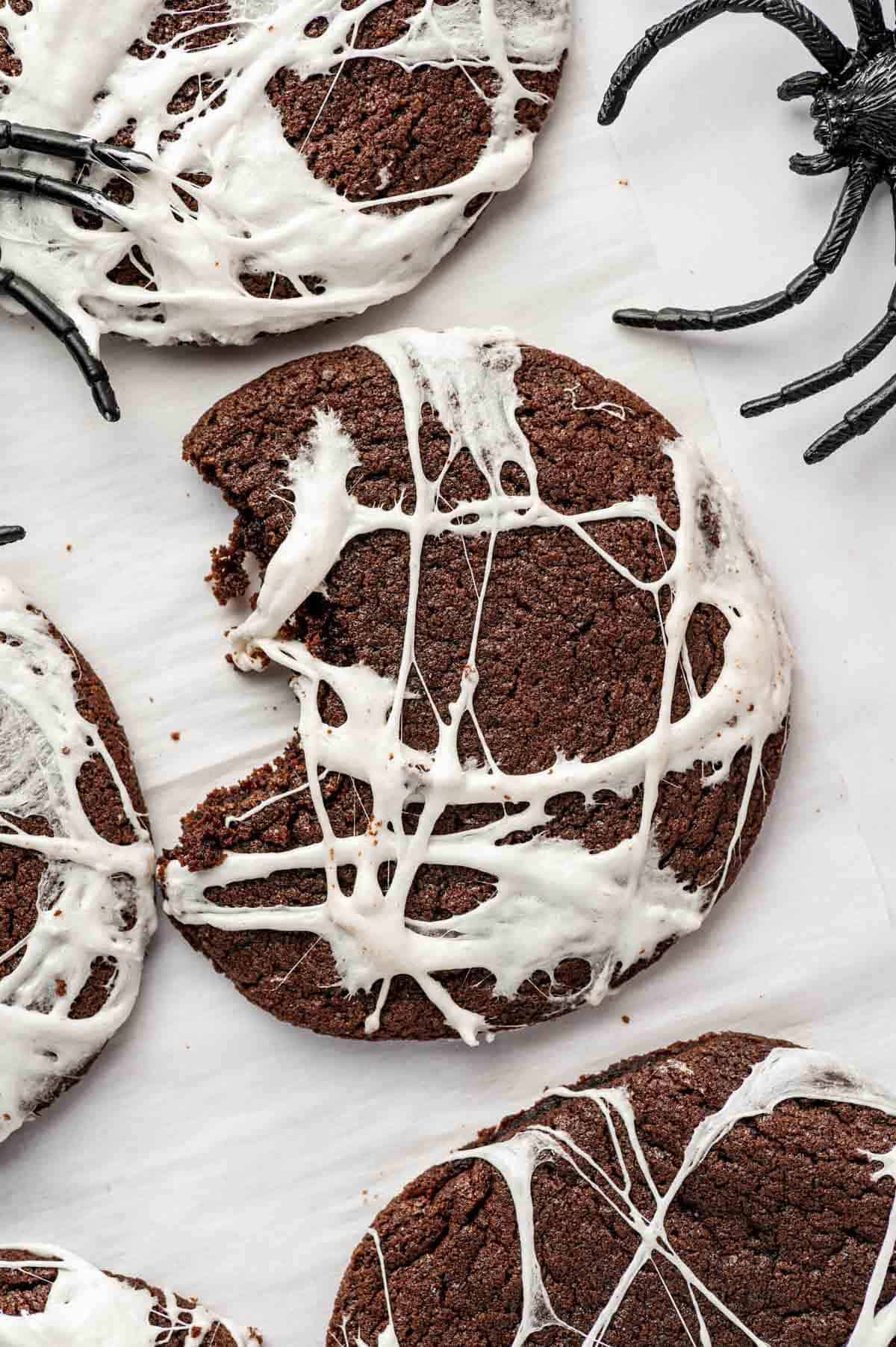 A bite taken of Soft chocolate Halloween cookies topped with melted marshmallow webs
